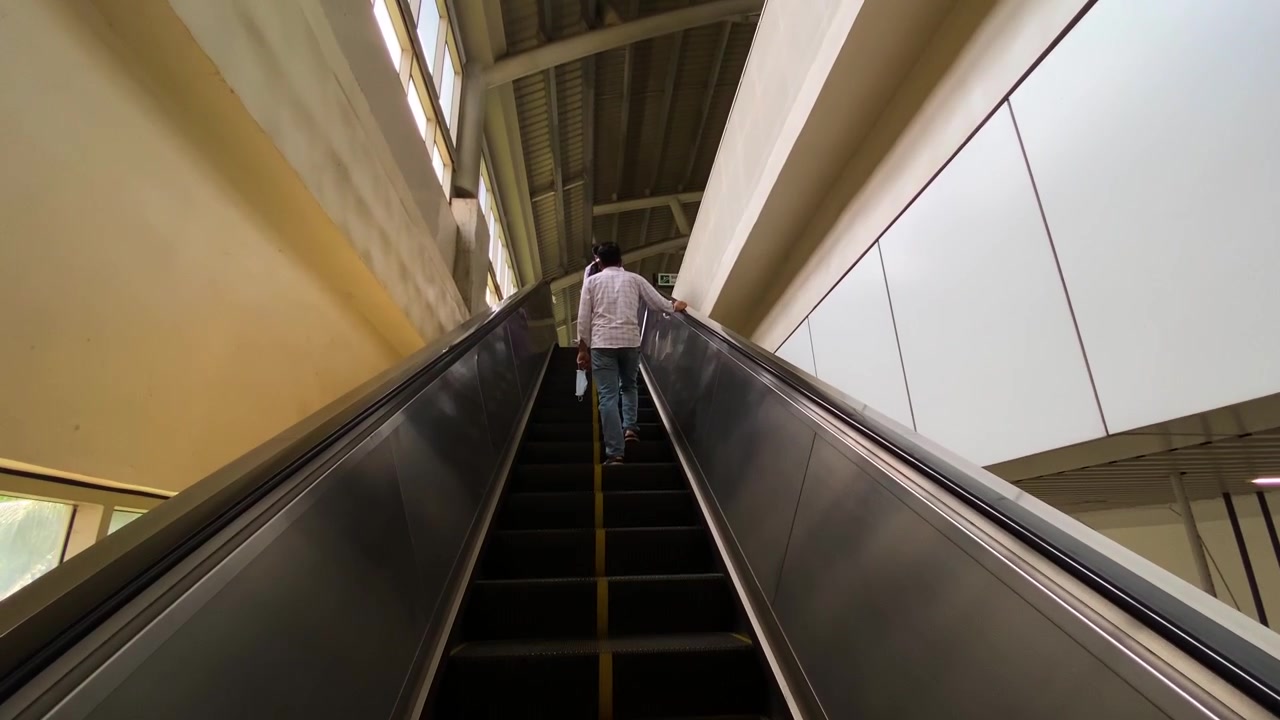 Hombre en escalera mecánica, estación de metro, infraestructura moderna, Daca Bangladés, transporte público, viaje diario, viaje urbano, arquitectura editorial
