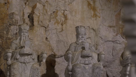 a group of stone statues depicting ancient kings, carved in a natural cave setting in vietnam