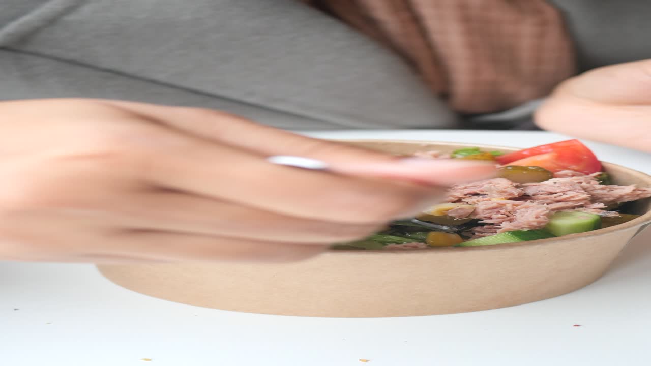 una persona comiendo una ensalada de atún