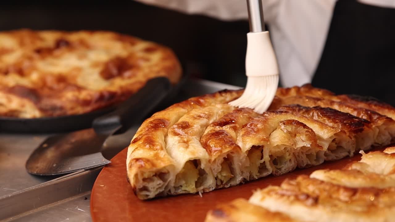 Primo piano di una mano che spennella un rustico salato appena sfornato.