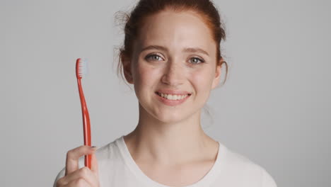 redheaded girl in front of camera on gray background.