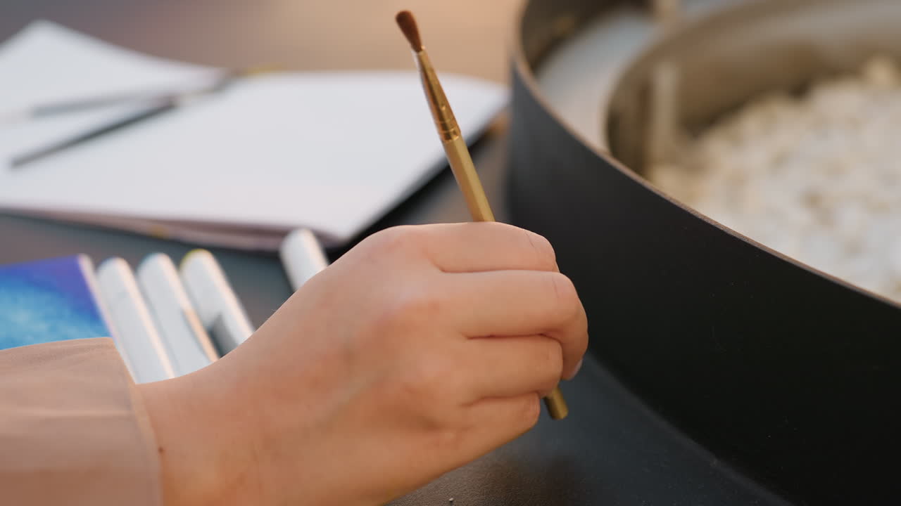 Художник подготавливает материалы, спокойный художник раскладывает инструменты для рисования, женщина-творец сосредоточенно организует принадлежности для акварели, человек спокойно раскладывает инструменты для рисования в тихой студии