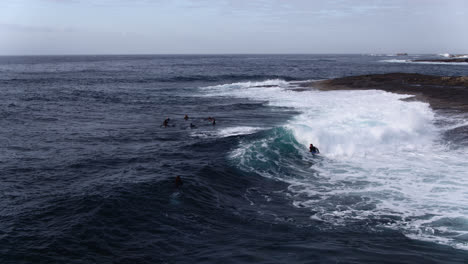 aerial tracking a group of surfers and bodyboarders riding waves close to rocks