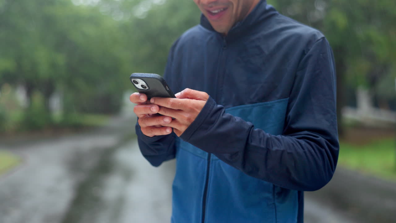 비가 오는 동안 스마트폰을 사용하는 남자