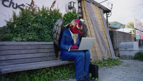 Tengu-Businessman-sitting-on-Bench-in-Fukusaki-Yokai-Town,-Japan-4k