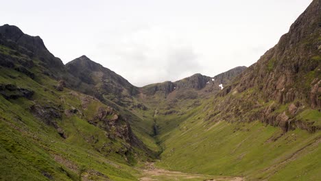 Eine-Dramatische-Luftaufnahme,-Die-Ein-Wunderschönes-Tal-Hinter-Einem-Großen-Felsen-Im-Schottischen-Hochland-Enthüllt-|-Das-Verlorene-Tal,-Glencoe,-Schottland-|-Aufnahme-In-4k-Mit-30-Fps