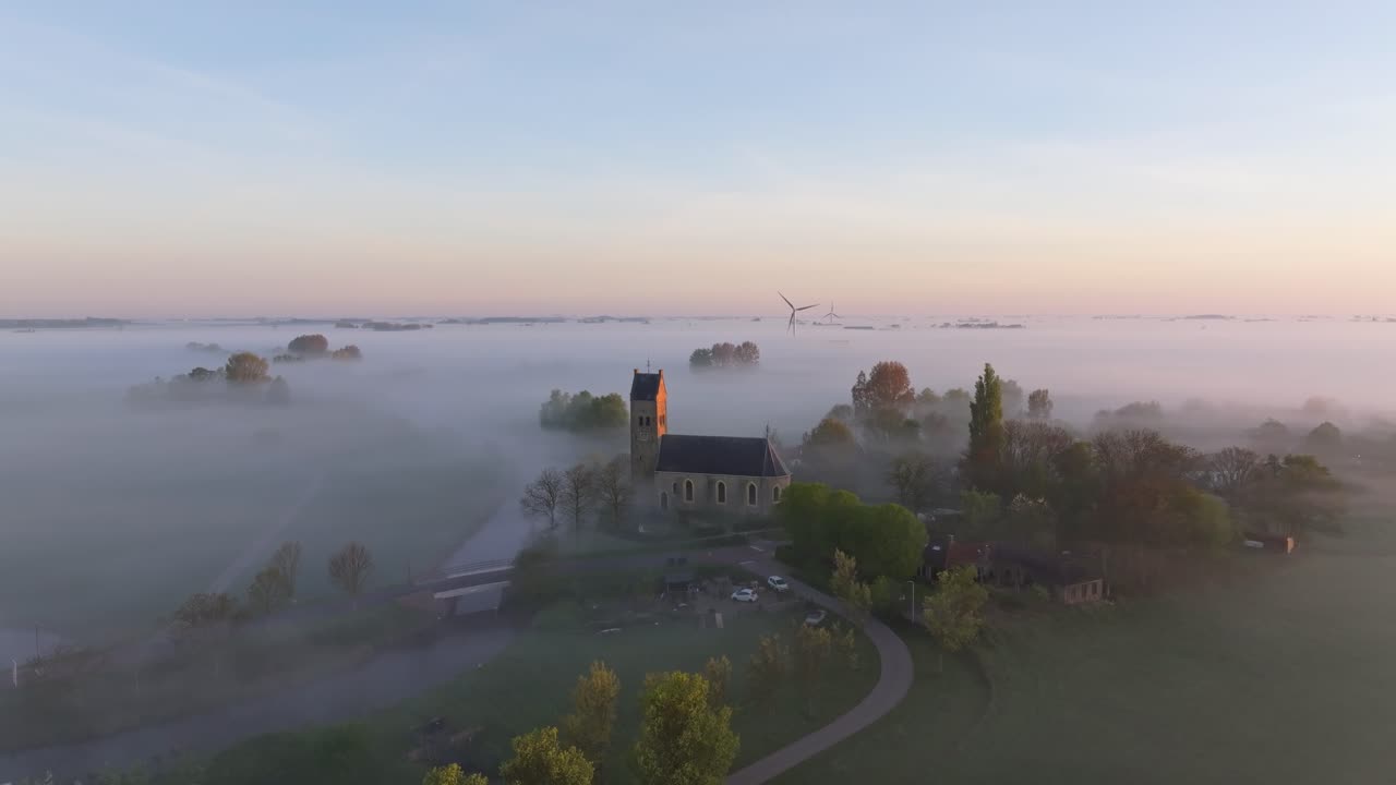 Aerial view of river beside church in soft morning fog, Hichtum