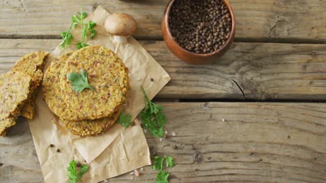 Video-of-fresh-leaves-and-vegetarian-burgers-with-bowl-of-peppercorns-over-wooden-background