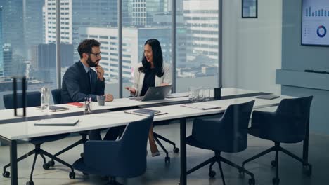 businesspeople in modern office: businesswoman and businessman use laptop computer, talk. top manager and partner investor discuss e-commerce software global investment strategy. elevating wide shot