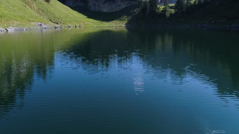 Toma-Aérea-Del-Lago-De-Montaña-Azul-En-Los-Alpes-Suizos,-Reflejo-Del-Agua,-Falensee,-Aplstein