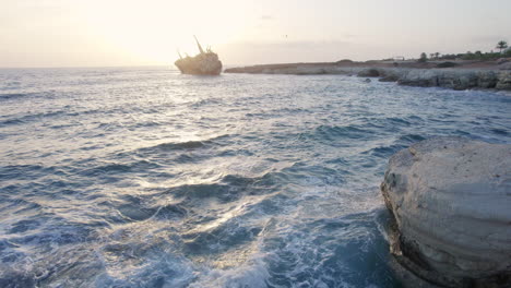 a mesmerizing view of waves at sunset near the edro iii shipwreck off the coast of cyprus, capturing the beauty of the sea and the dramatic shipwreck