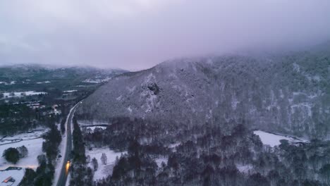 Von-Weitem-Sichtbare-Scheinwerfer,-Die-Eine-Straße-Entlang-Durch-Die-Winterliche-Landschaft-Fahren