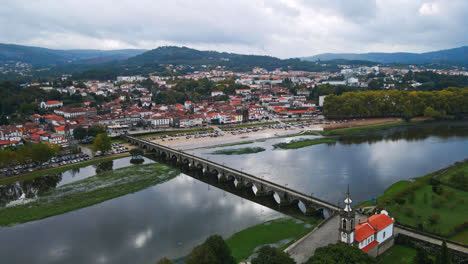 Stunning-aerial-4K-drone-footage-of-a-village---Ponte-de-Lima-in-Portugal-and-its-iconic-landmark---Stone-roman-bridge-crossing-over-the-Lima-River