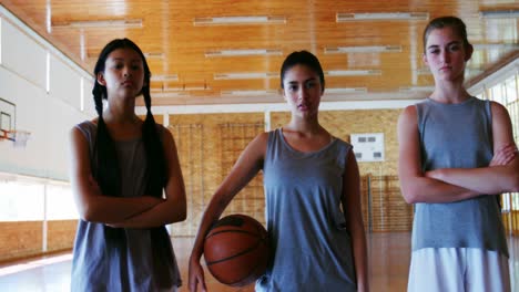 Portrait-of-schoolgirls-holding-basketball-in-basketball-court