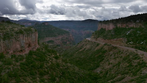 Drone-shot-flying-into-large-canyon-area-with-inviting-road