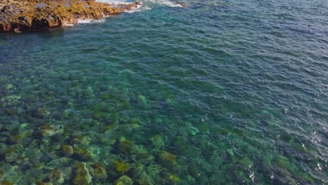 Crystal-clear-ocean-water-near-island-of-Tenerife,-aerial-drone-tilt-up-view