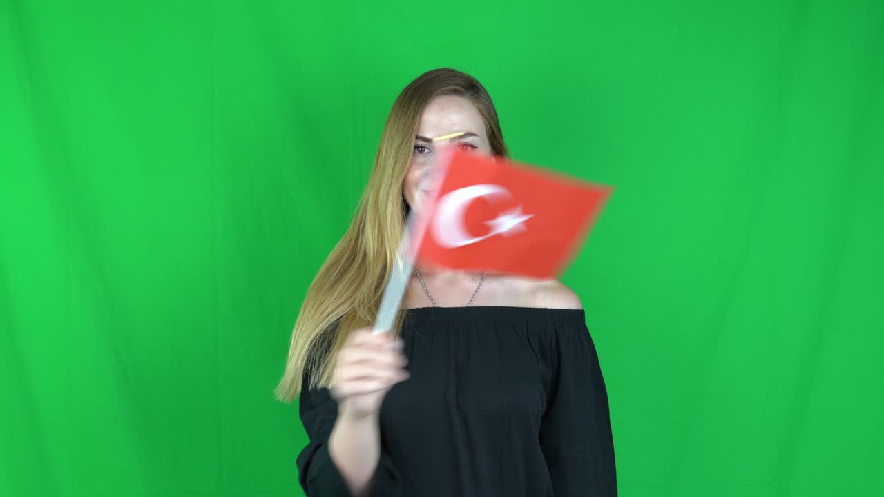 joven mujer rubia agitando delante de la bandera del pavo pantalla verde, fondo clave de croma