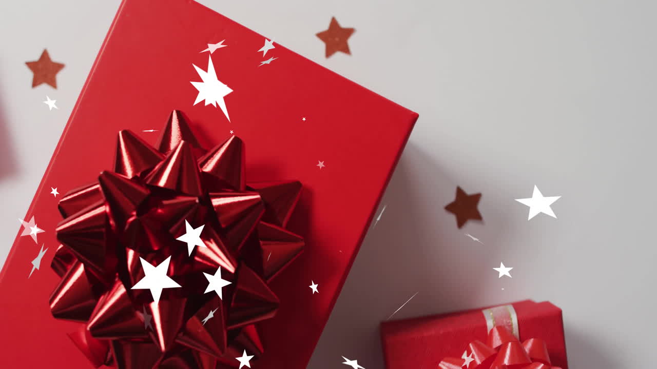 Animation of stars falling over christmas gifts and decorations on white background