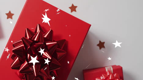 animation of stars falling over christmas gifts and decorations on white background