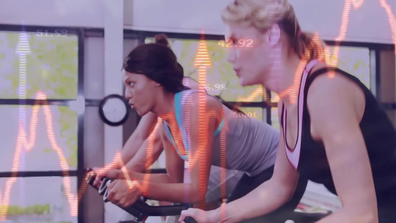 Colegas de academia começando o treino segurando os guidões com gráficos de frequência pulsando em bicicletas ergométricas