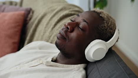 man sleeping on couch with headphones