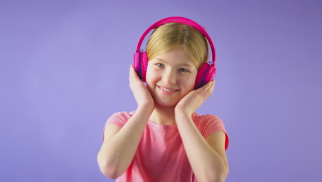 studio portrait of girl with wireless headphones streaming music against yellow background