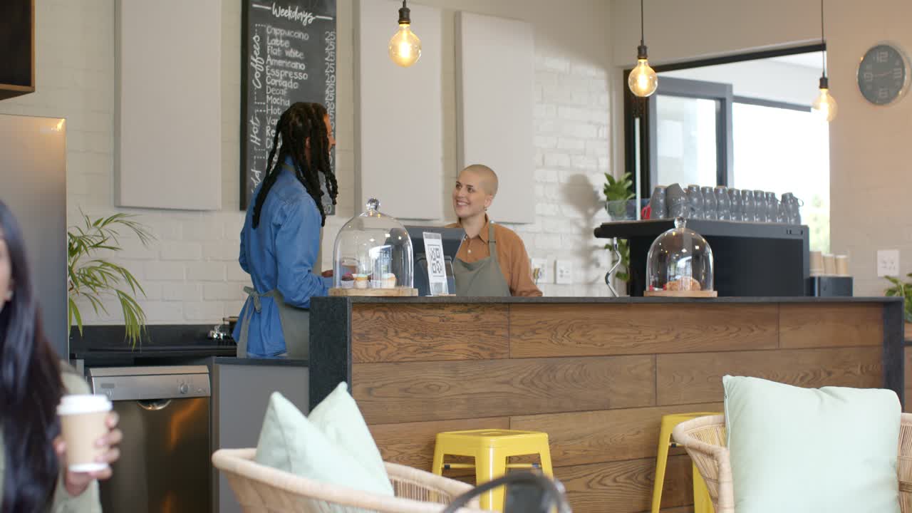 Diversi colleghi che danno un'occhiata al menu e poi indicano una cupola di vetro mentre sollevano pasticcini dietro al bancone del caffè