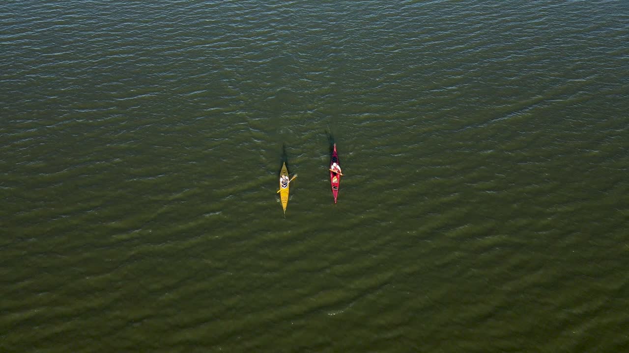 kayaks remando a través de un lago al atardecer