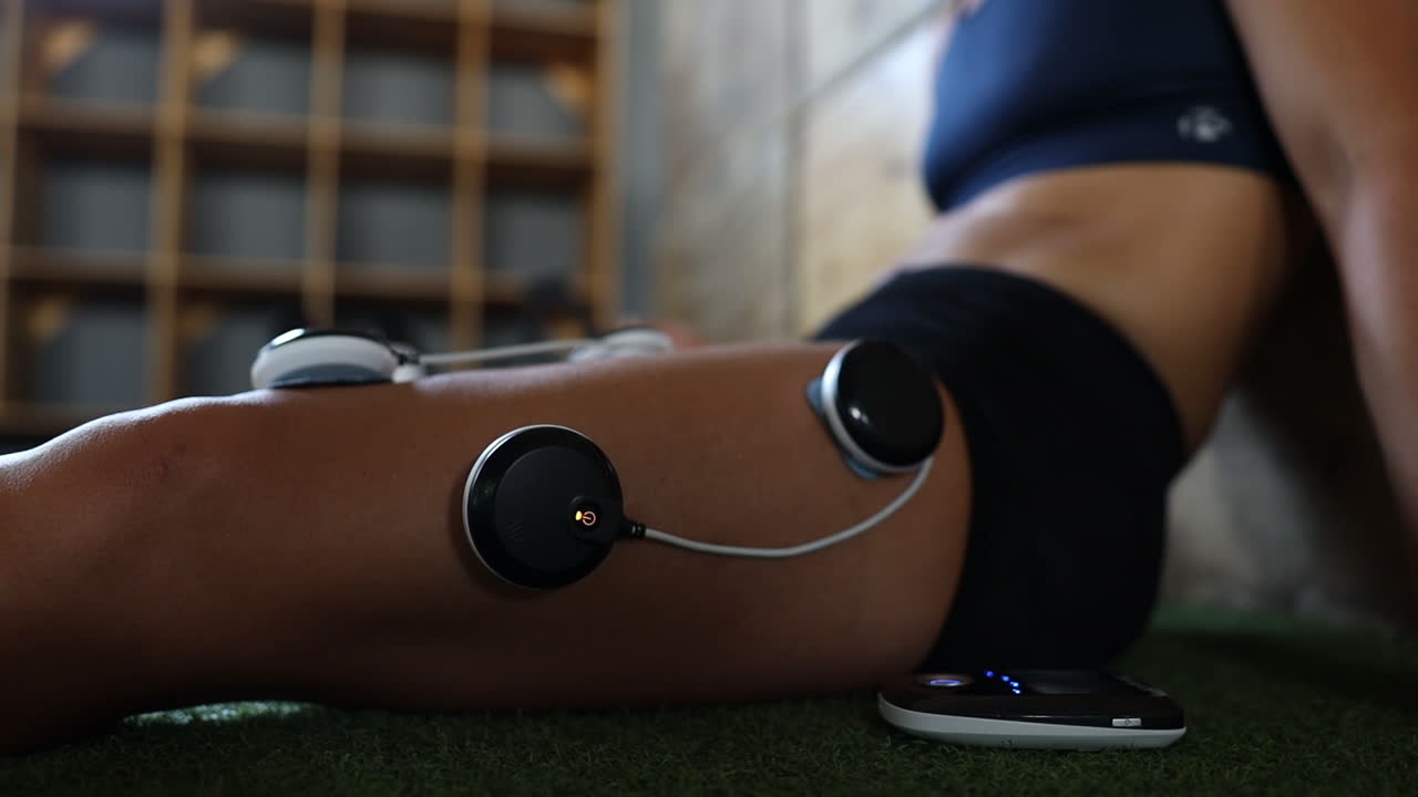 close up footage of electro vibration massage pads being used on an athletes legs