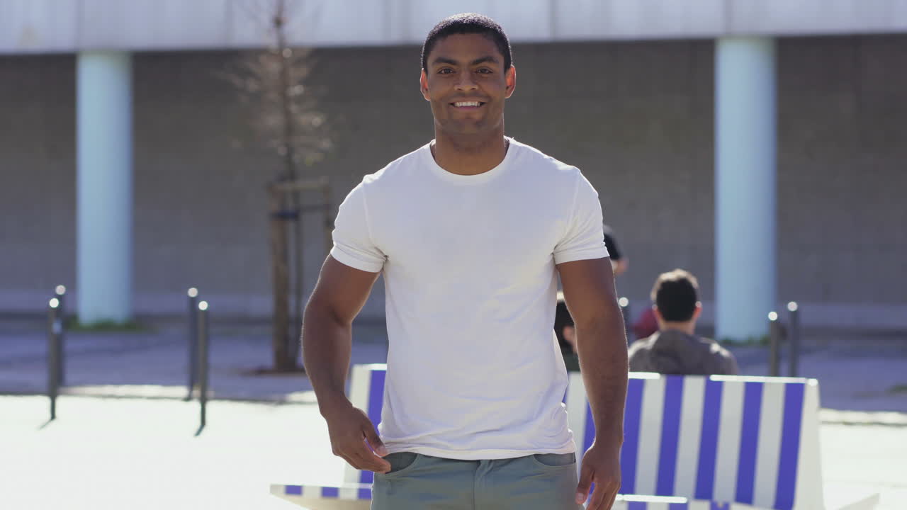 un deportista sonriente de pie en la calle con las manos en los bolsillos.