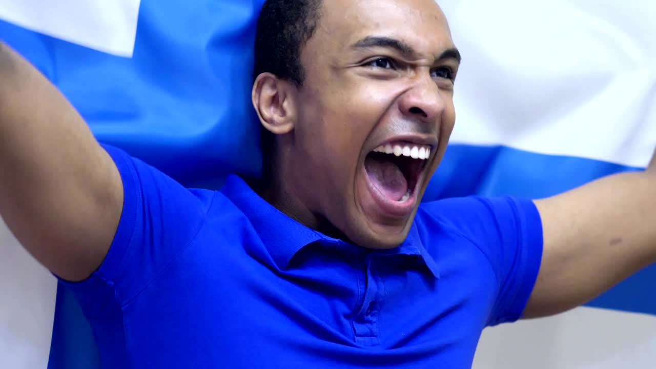 fanático finlandés celebrando mientras sostiene la bandera de finlandia en cámara lenta