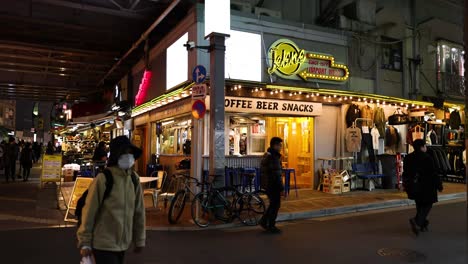 pedestrians walking past shops at night