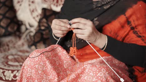 Traditional-Indian-woman-siting-and-knitting-with-red-and-black-wool
