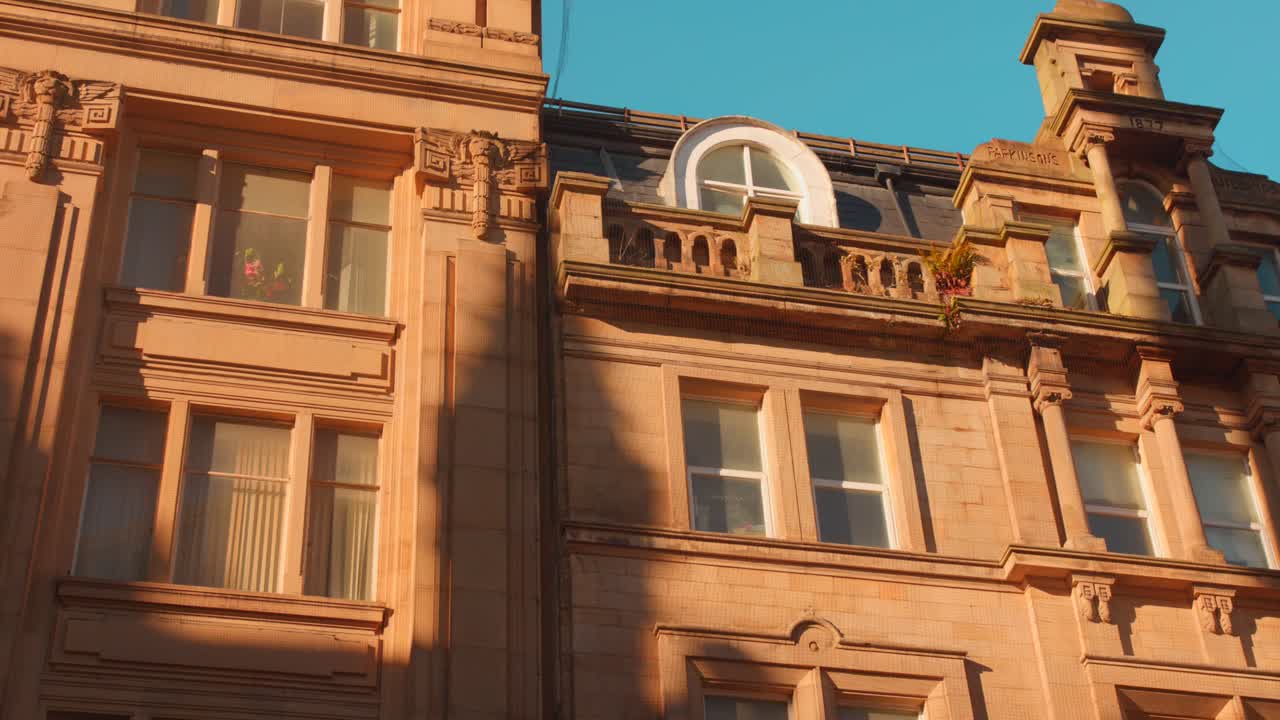 Facciate in arenaria di epoca vittoriana a Bradford. Muratura decorata, archi classici e dettagli architettonici che risplendono sotto un caldo cielo al tramonto