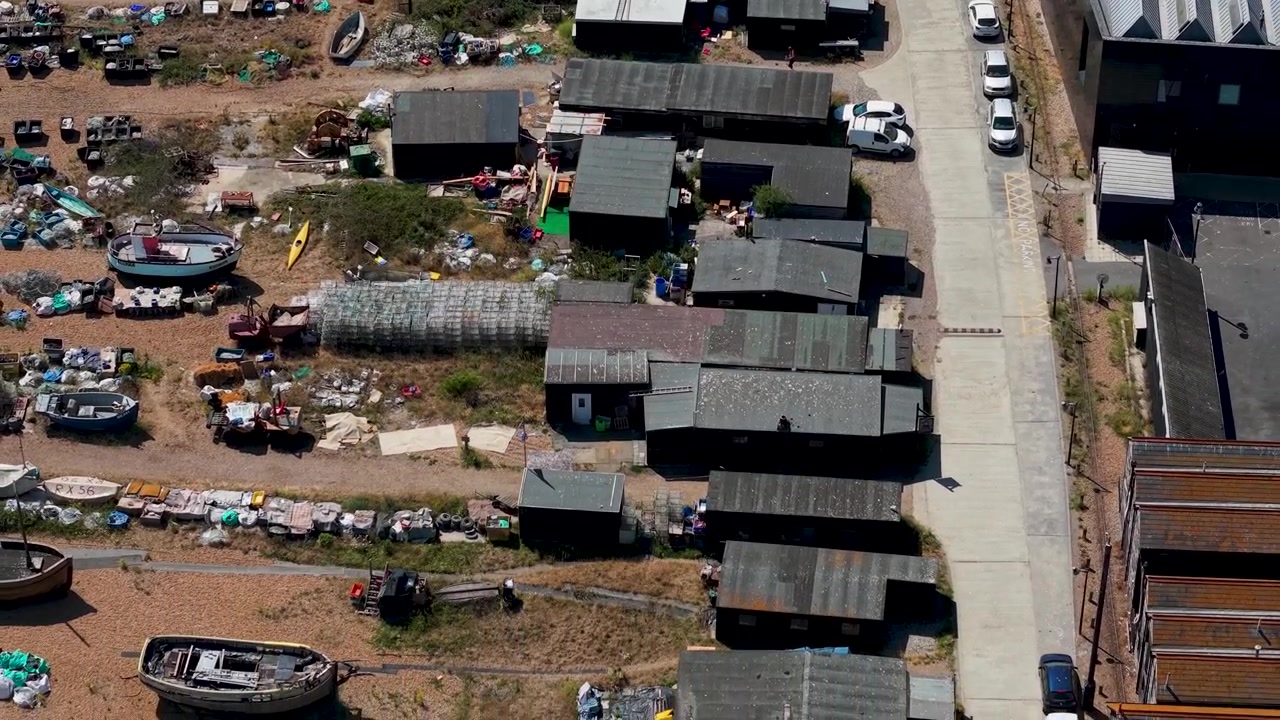 Un dron se aleja de los cobertizos de pesca de techo negro y los barcos dispersos por Hastings Stade en esta vista aérea.