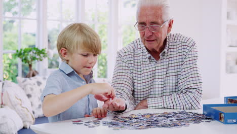 senior man and grandson doing jigsaw puzzle together at home