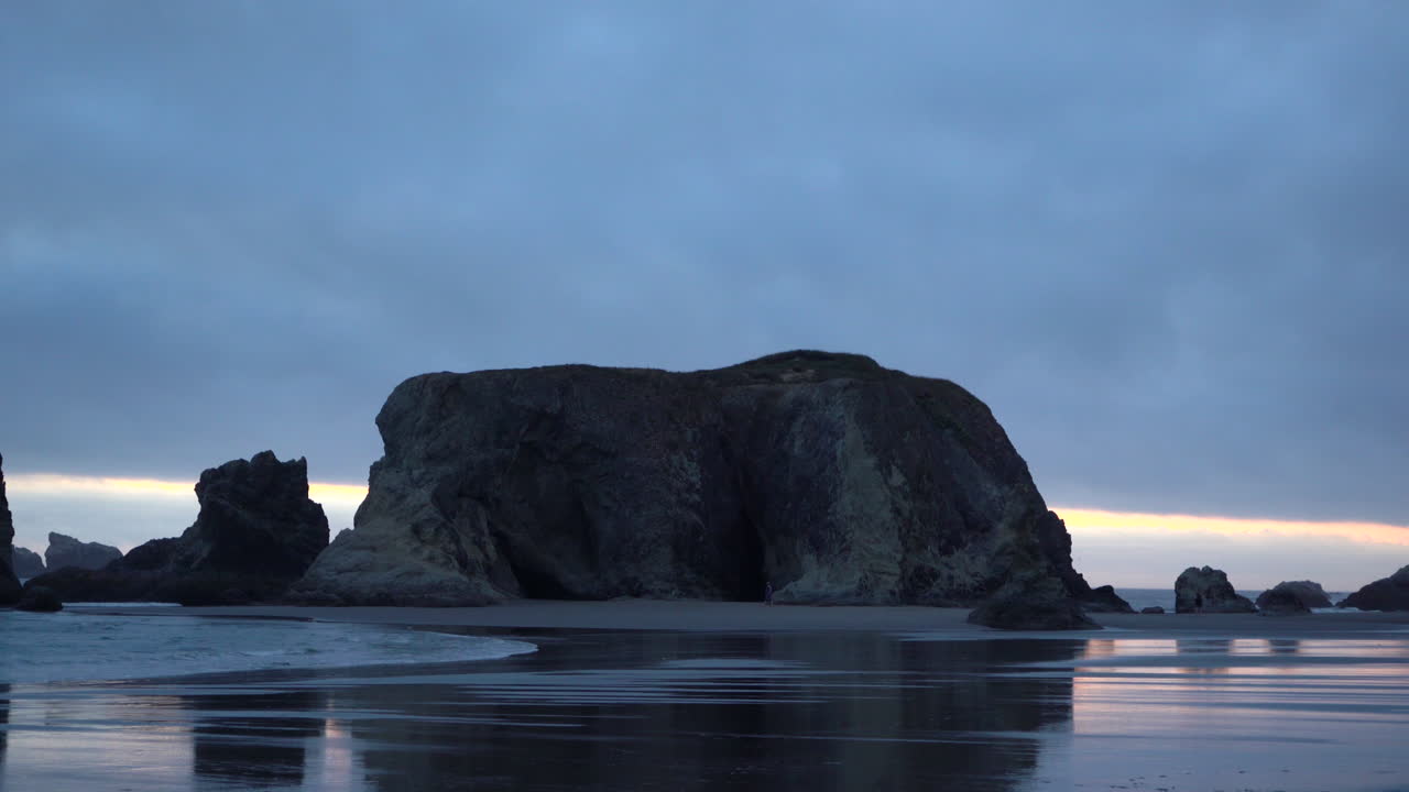 escena de la playa de la hora azul en bandon, oregon, paisaje espectacular e impresionante, gente irreconocible en la playa