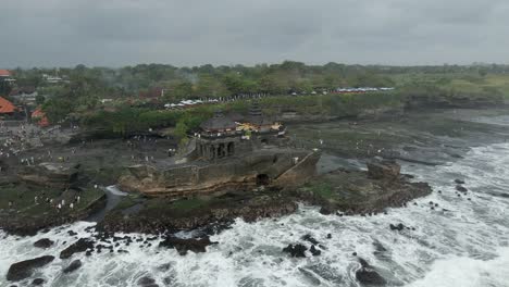 aerial view: grey ocean waves splash, crash on rocks at tanah lot bali