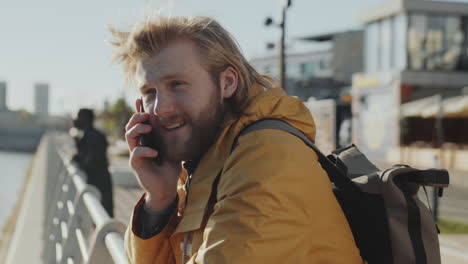 man chatting on cell phone on urban embankment