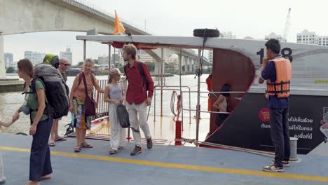 tourists get off a boat after taking a boat tour on the chao phraya river, thailand