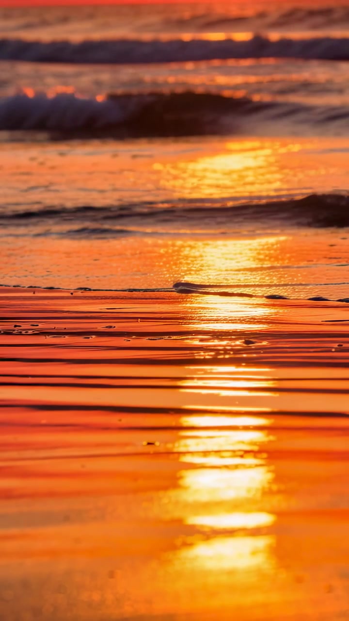Solrefleksjon på våt, krusete sand som reagerer på små bølger, skifter og avslører skum for fotografering.