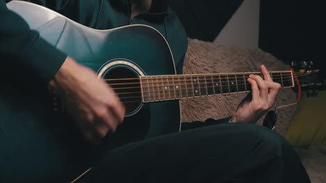 man plays a pick on a modern guitar in the dark