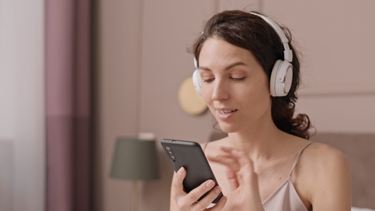 Woman listening to music with headphones in bedroom