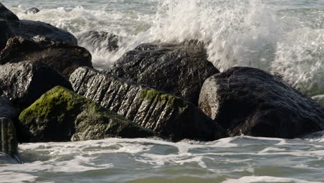 wide shot slow mo shot of waves crashing over rocks at hurst spit