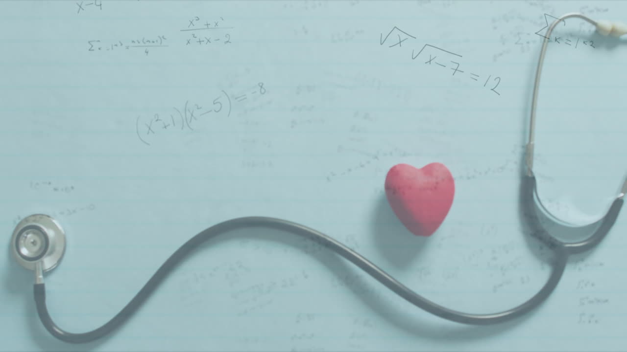 Red heart-shaped stress ball resting on pencil math sheet, stethoscope tubing arcing across page