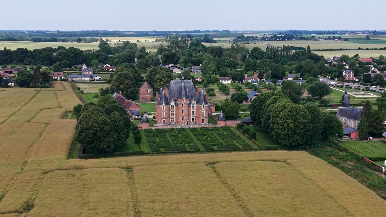 Vista cinematográfica lenta de drone do Castelo de Martainville a uma distância maior, revelando o castelo, as terras agrícolas circundantes e a paisagem rural na Normandia, França