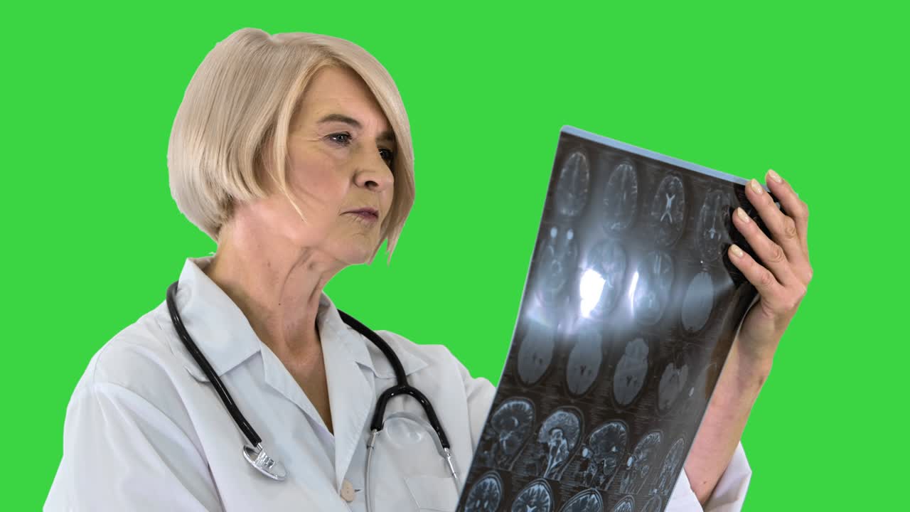 una mujer médico senior mirando una resonancia magnética en una pantalla verde, llave de croma