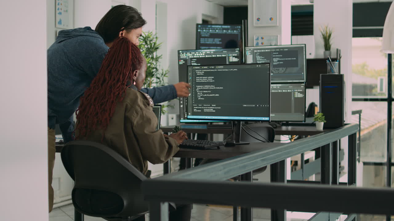 Diverse team of ai cloud programers talking about coding script in front of computer