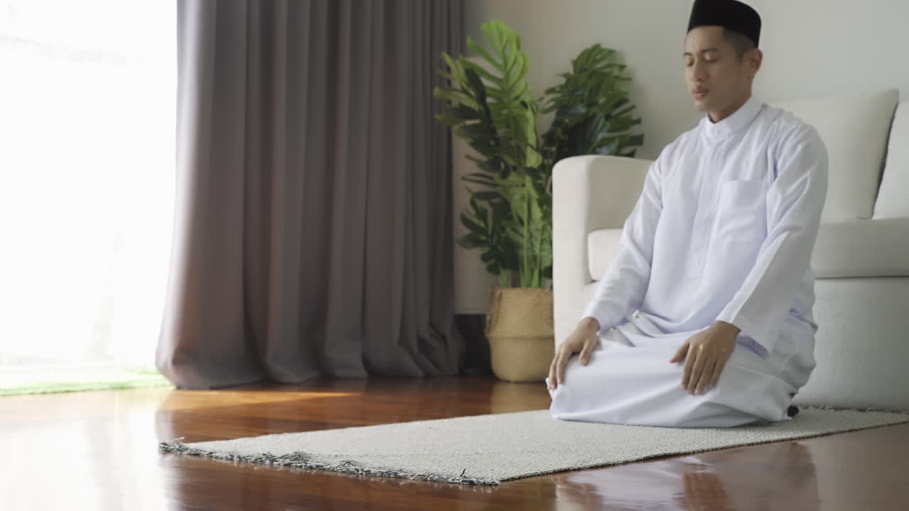 Asian Muslim man reciting surah al-Fatiha passage of the Qur'an, in a daily prayer at home in a single act of sujud called a sajdah or prostration