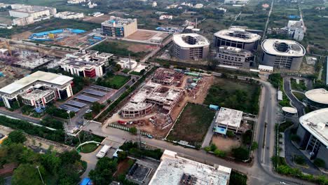 aerial video of chennai township completed modern buildings with distinct architectural designs, alongside significant areas of active construction, with unfinished structures and visible machinery.